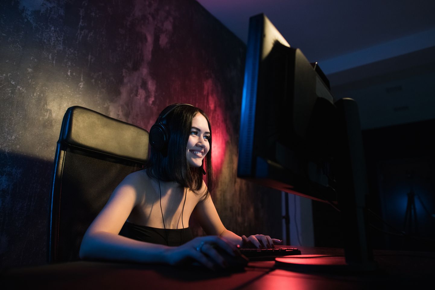 Girl Playing MOBA Games Like LoL on a Computer with Red Lights Behind Her