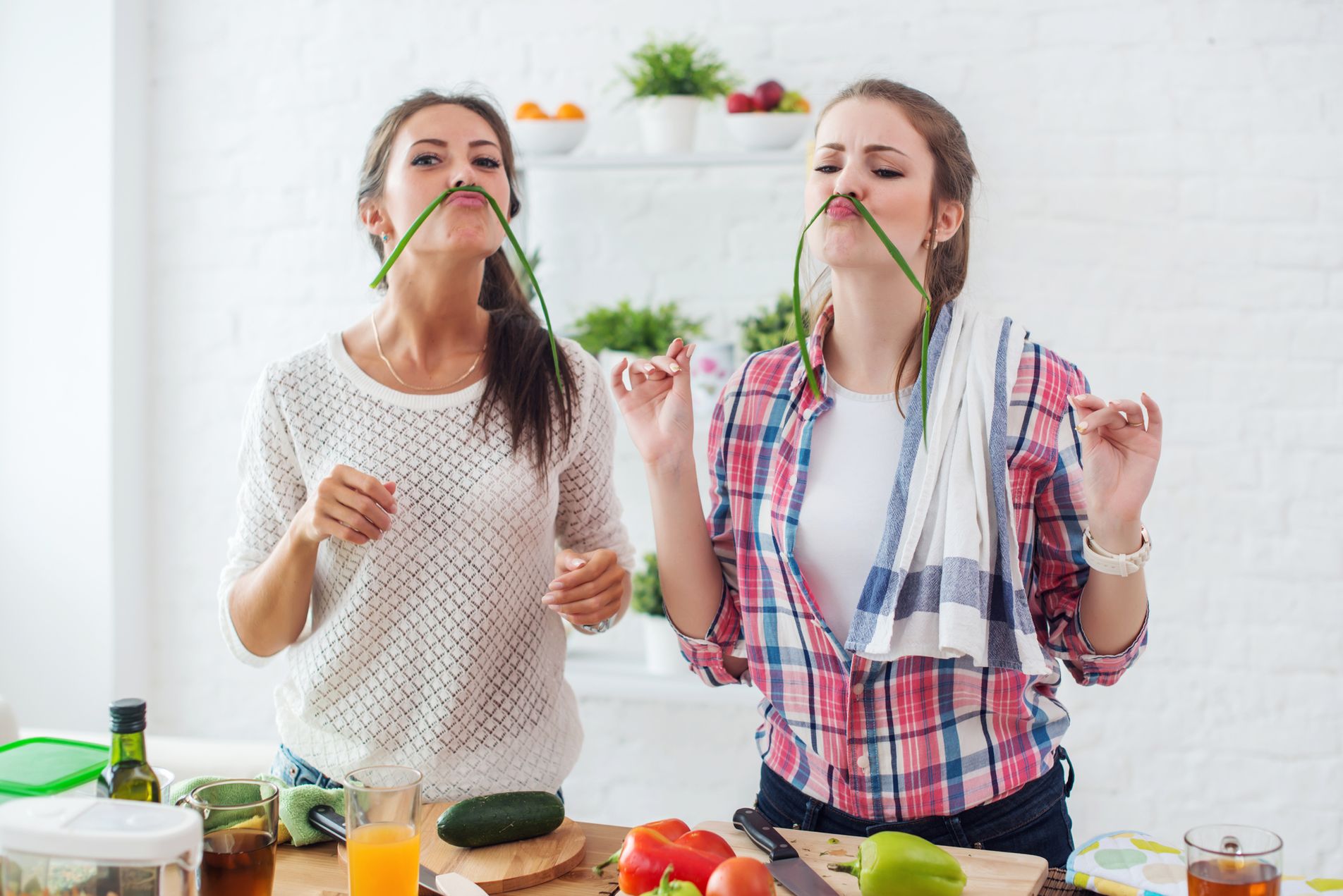 Women preparing healthy food playing with vegetables in kitchen having fun concept dieting nutrition
